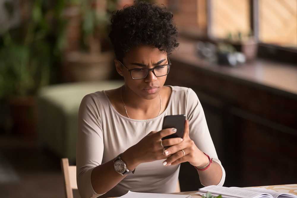 A woman looks at her phone with a puzzled face